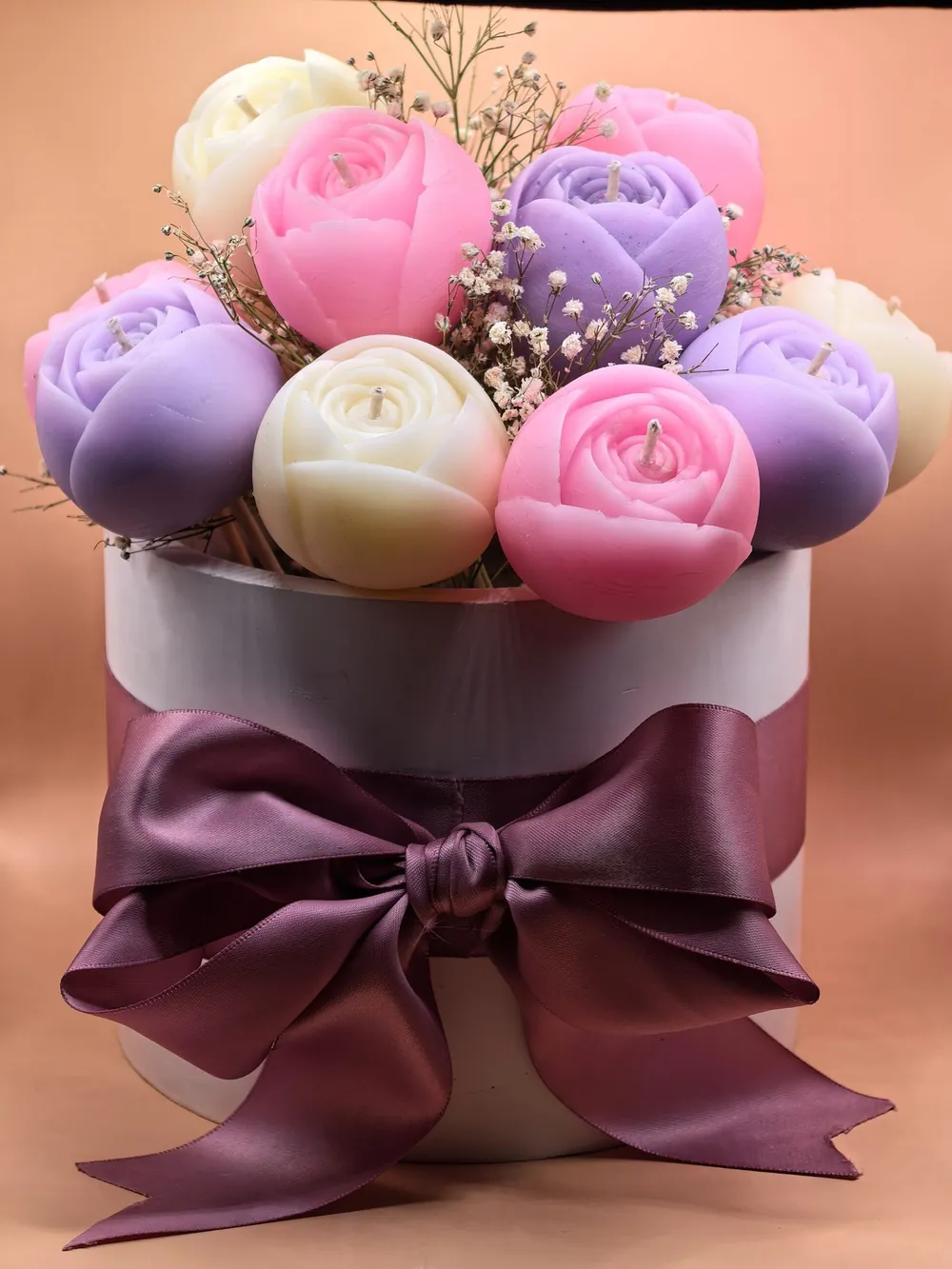 Bouquet de velas en forma de rosas y tulipanes en rosa, lavanda y marfil, con moño color ciruela