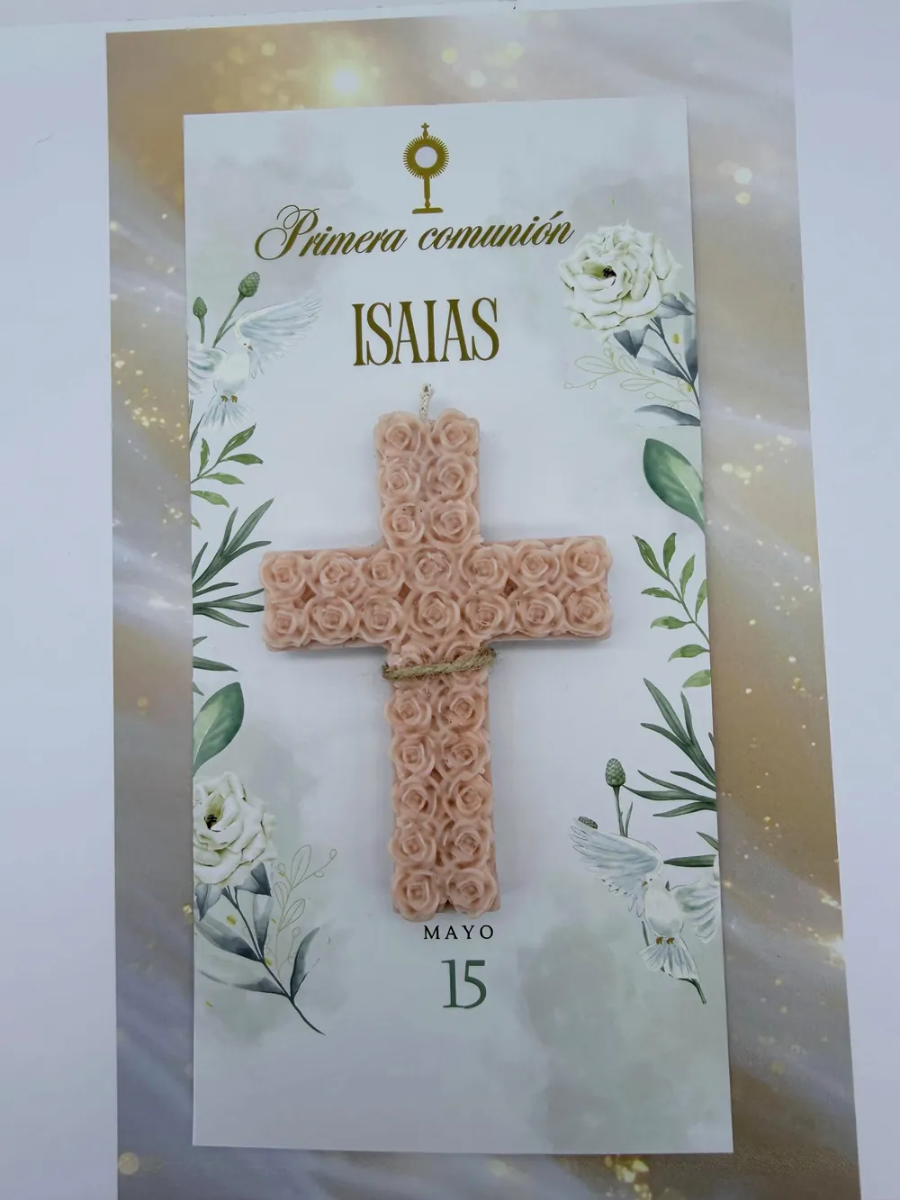Vela en forma de cruz cubierta de rosas sobre una tarjeta personalizada de primera comunión