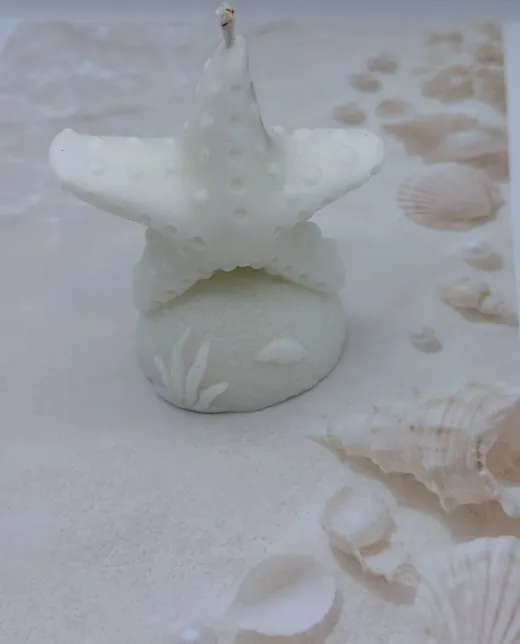 Vela en forma de estrella de mar sobre arena, recuerdo para boda en la playa