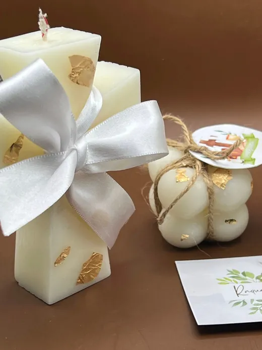 Velas recuerdo en forma de cruz y burbuja con moño blanco, detalles dorados y etiqueta
