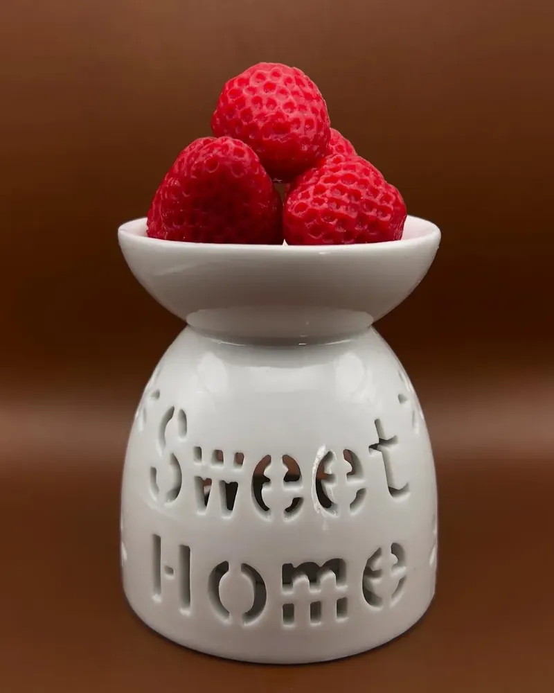 Wax melts en forma de fresa sobre un quemador de cerámica blanca con la leyenda Sweet Home