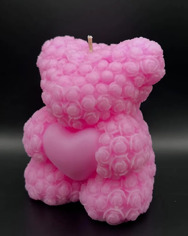 Vela rosa en forma de osito cubierto de mini rosas con un corazón al centro